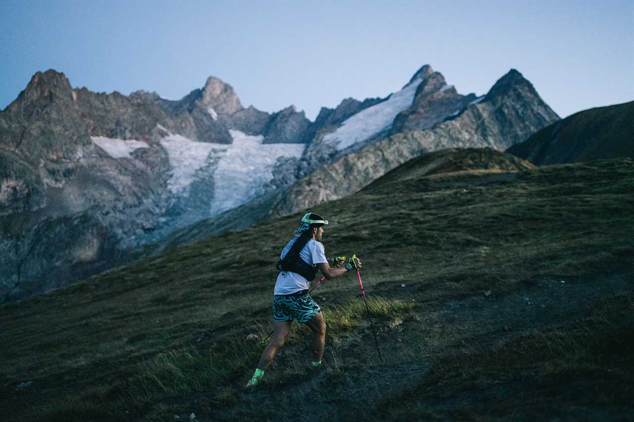 Man running up side of mountain with jagged peaks in background