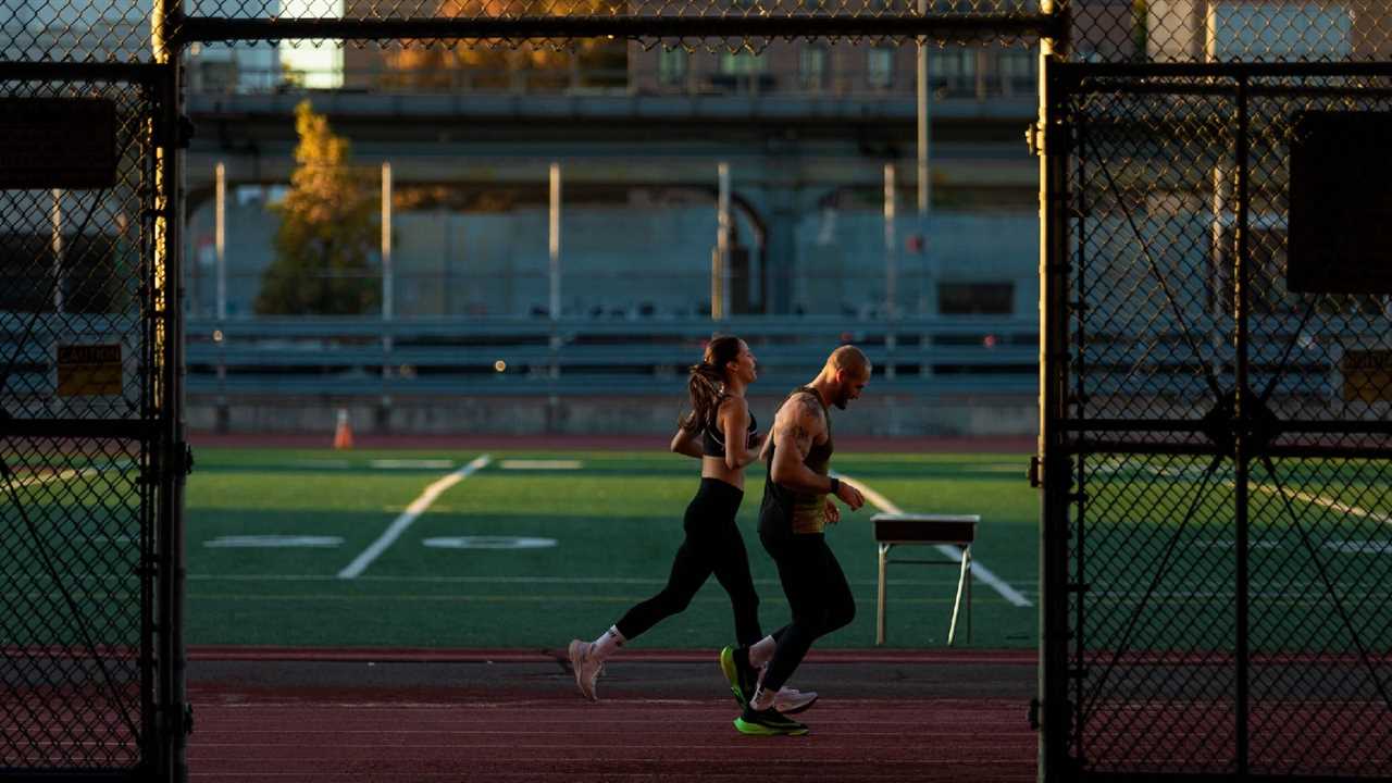 Male and female runners jogging on track