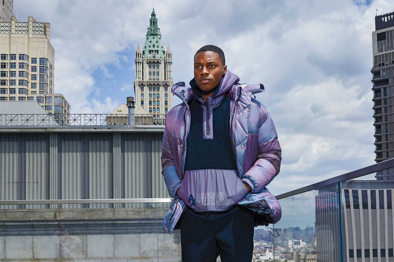 A man wearing a puffer coat jumps on a rooftop.