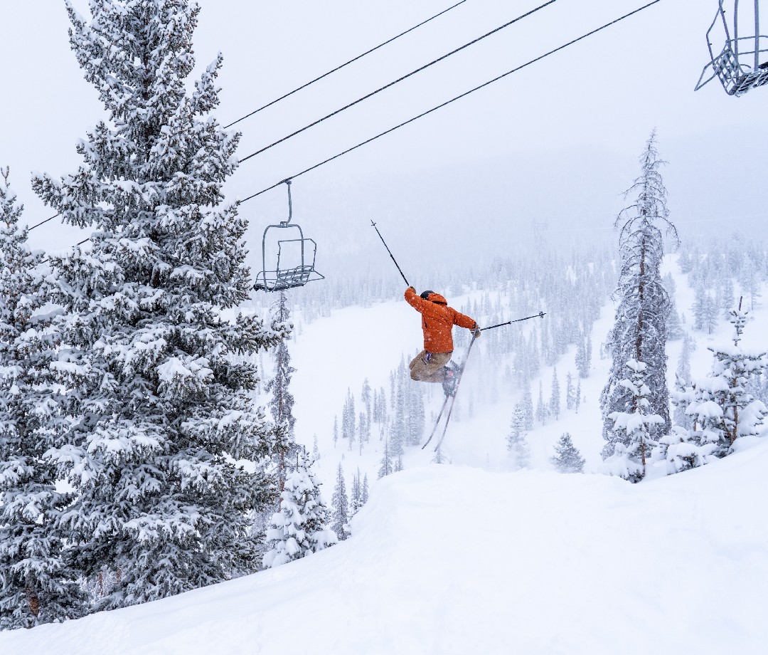 Skier taking a jump near a chair lift at Monarch Mountain