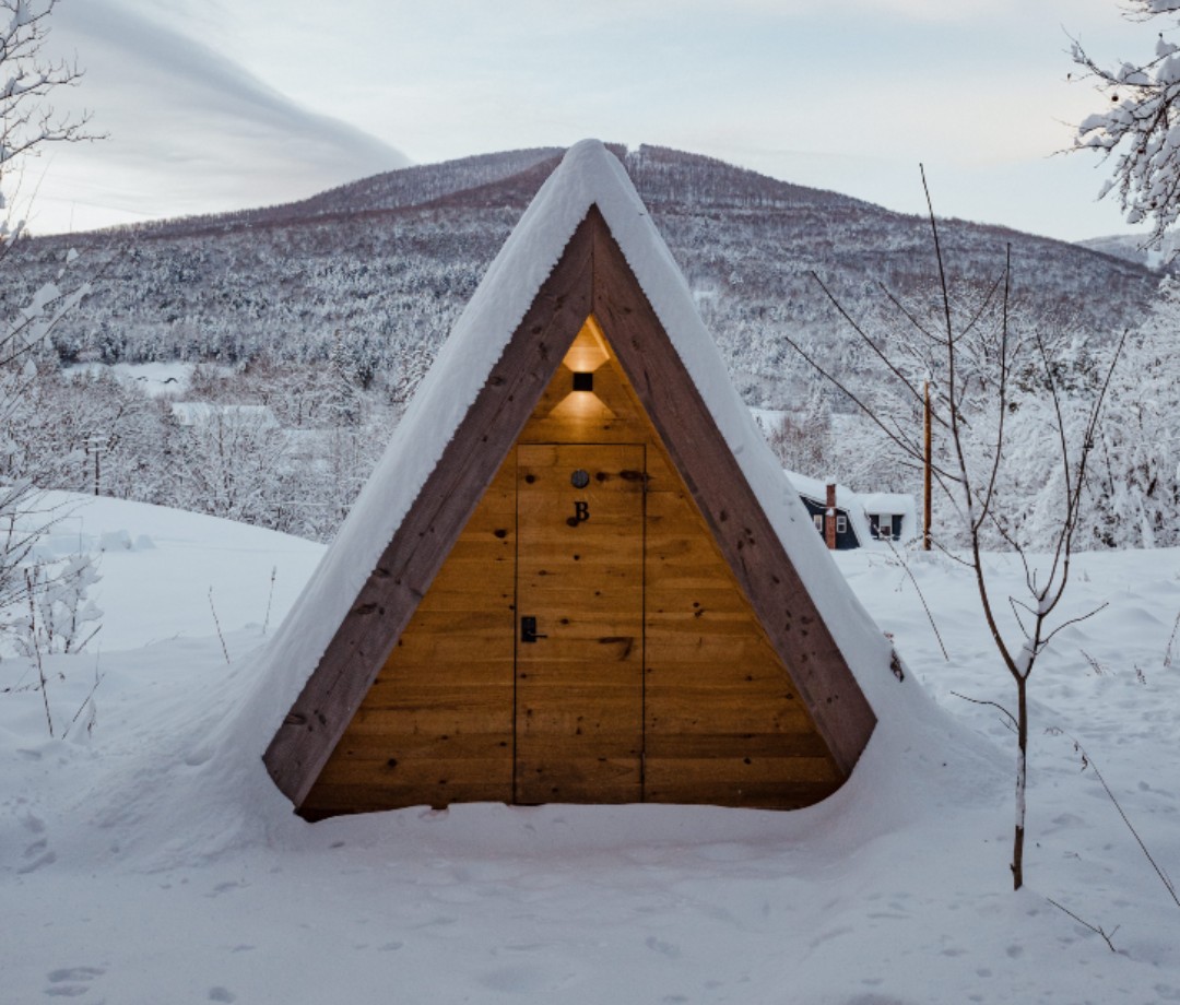 A-framr cabin in snowy landscape with mountain in background