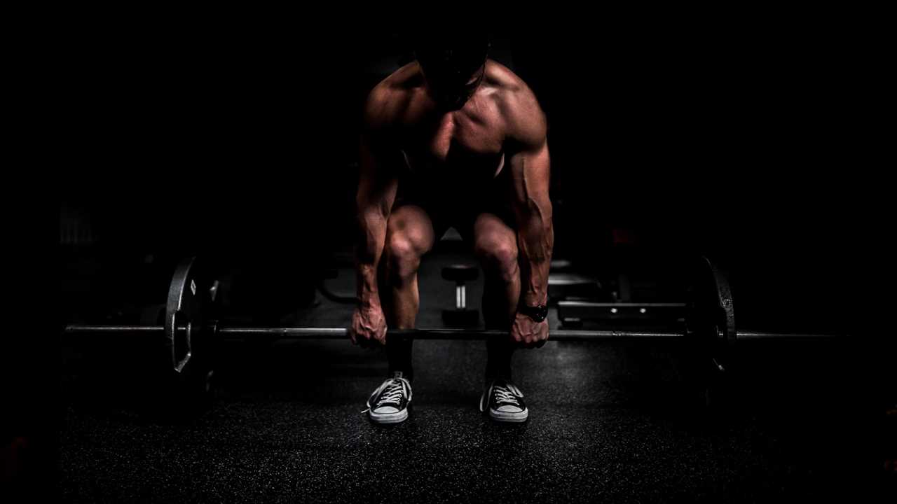 How to deadlift man holding a barbell on the floor