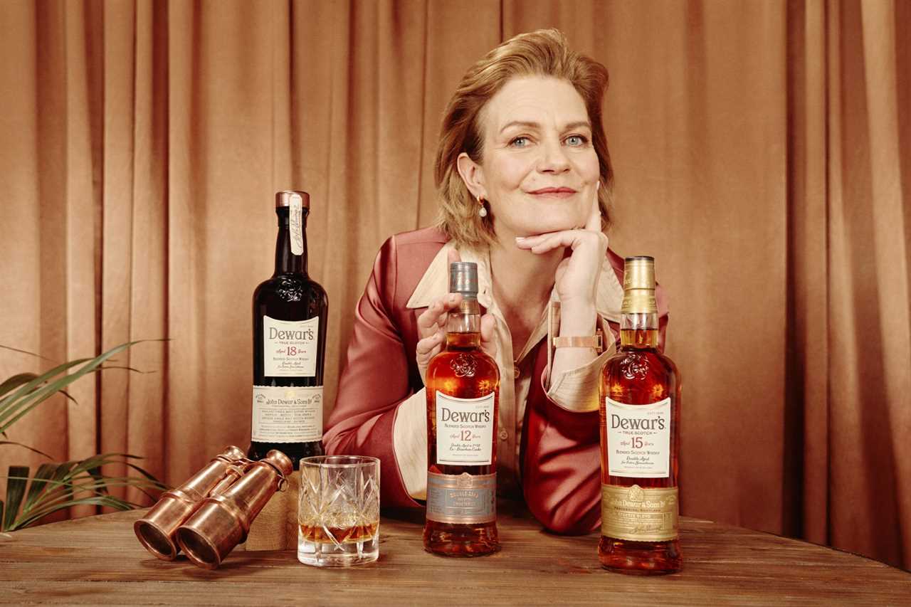 Mature caucasian woman posing with Dewar's whiskey bottles