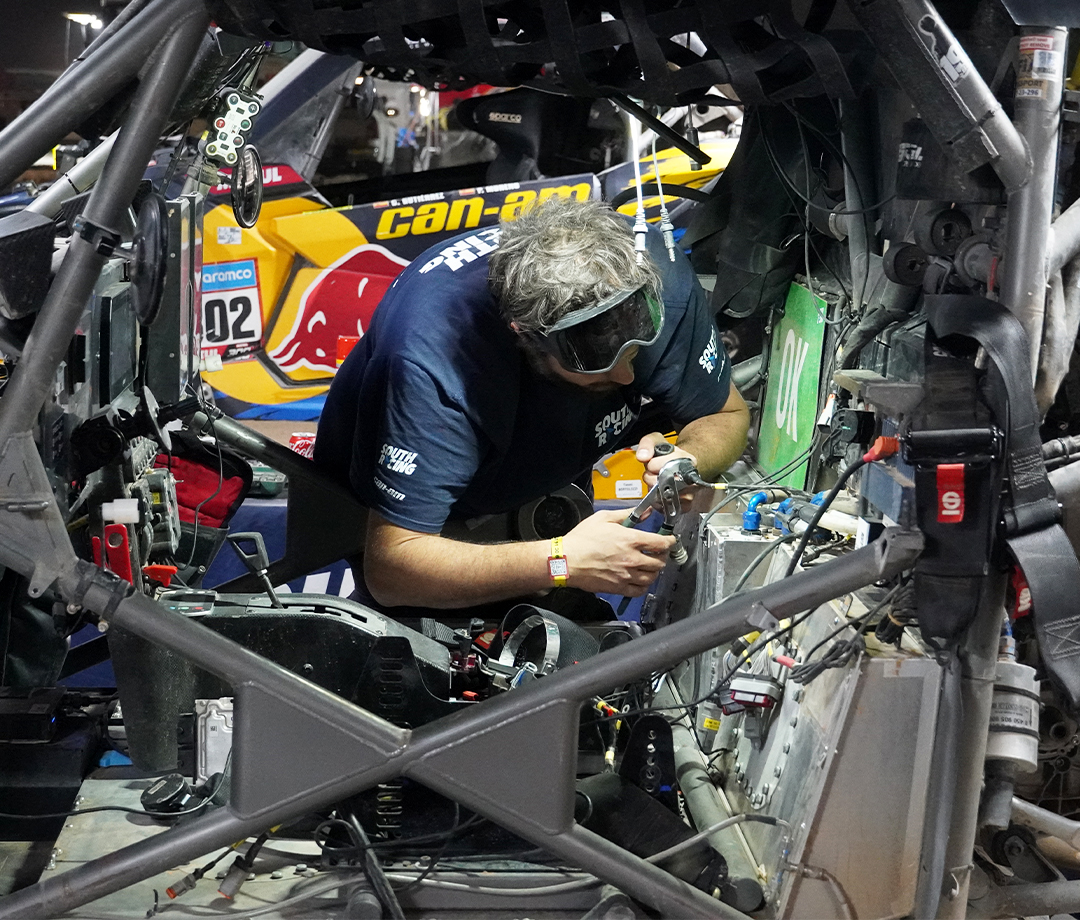 Mechanic working on a Dakar side by side off-roader with another in the background.