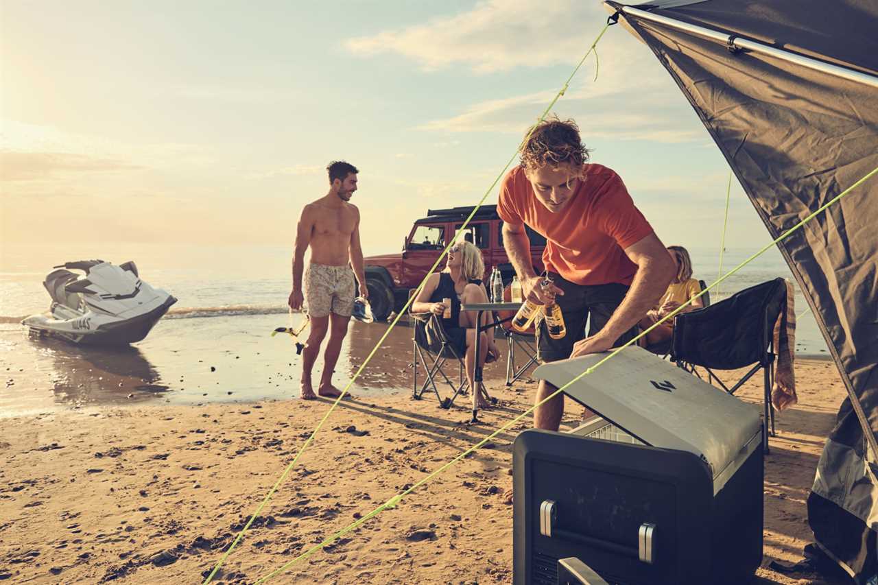 Group of men on beach reaching into cooler