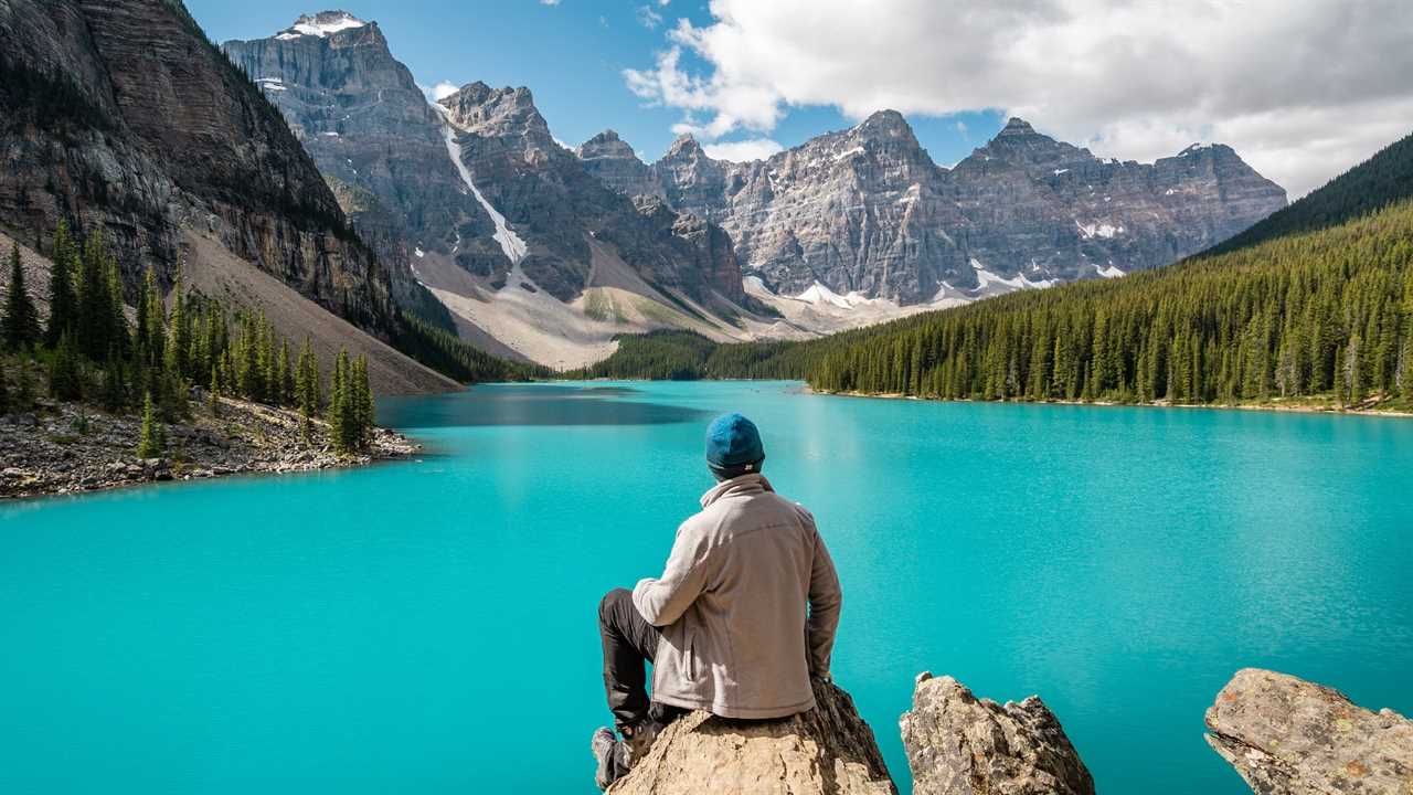 Hiker seated on a rock overlooking a turquoise lake in Banff National Park, Alberta.