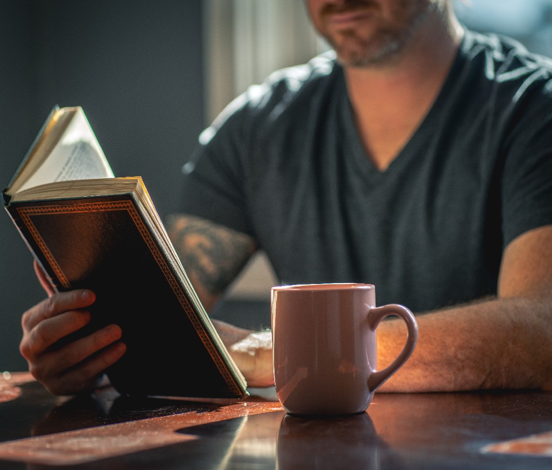 Man reading a book at a desk.