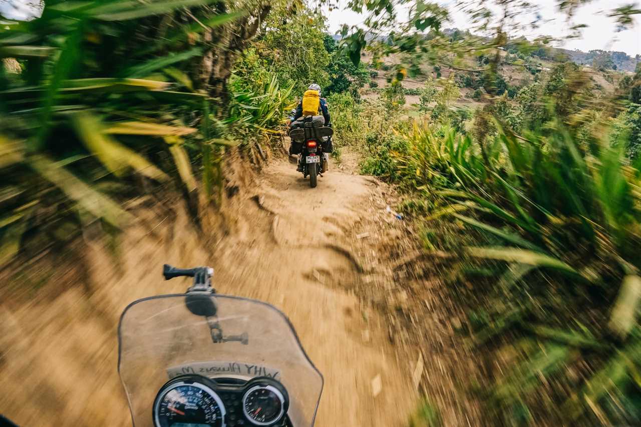 Motorcyling through dirt path with jungle vegetation