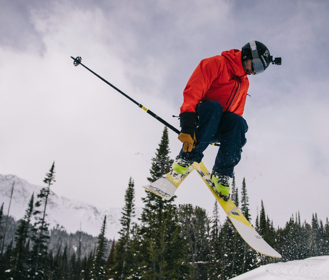 Skier in red jacket in mid-jump.