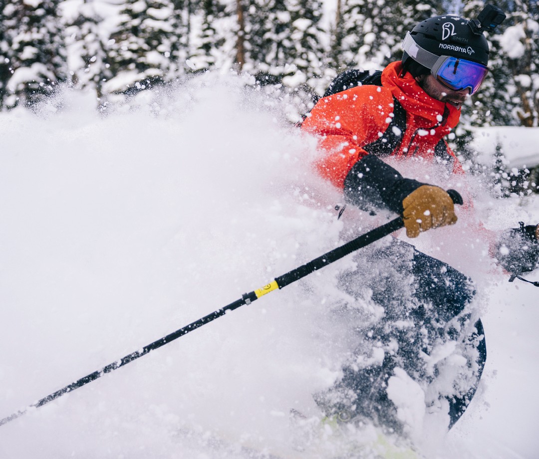 Closeup of skier in red jacket skiing through powder.