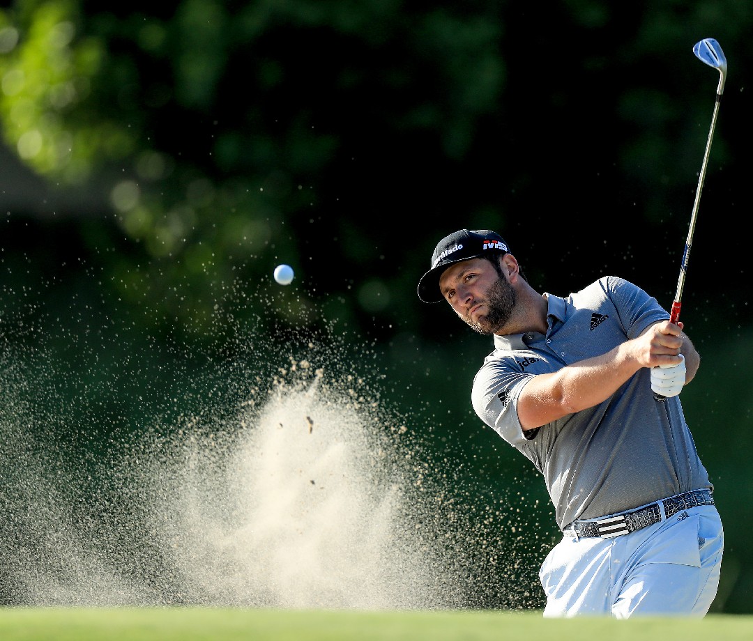 Jon Rahm chipping a ball onto the green.