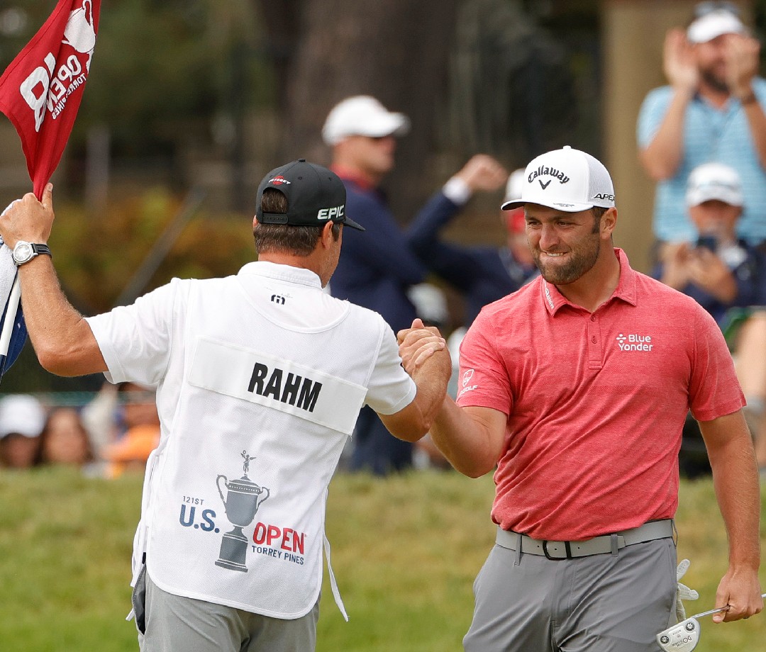 Jon Rahm celebrating with his caddy on the course.
