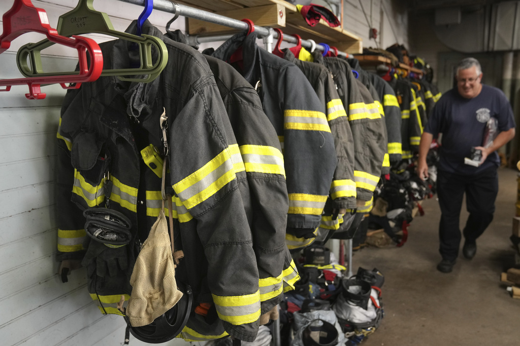 A Brockton, Mass., firefighter walks past protective gear at the station on Aug. 3, 2023.