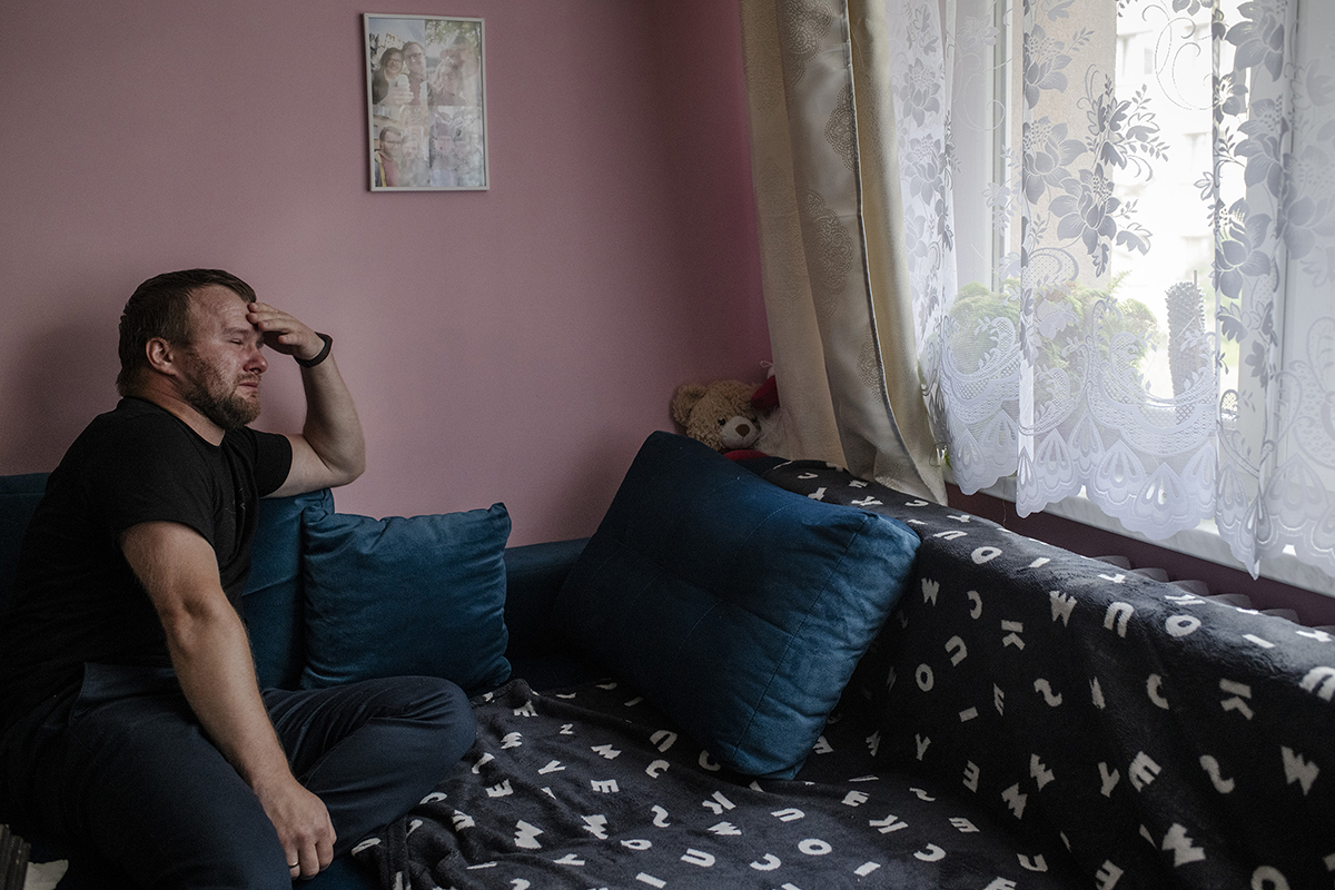 Krzysztof Sowinski sits on his couch in Dabrowa Gornicza, Poland, on July 31, where his late wife Marta rested in the days before she died. Over a year after Marta’s death, Krzysztof  has not moved anything from this couch or his display of ultrasound photos and other memorabilia.