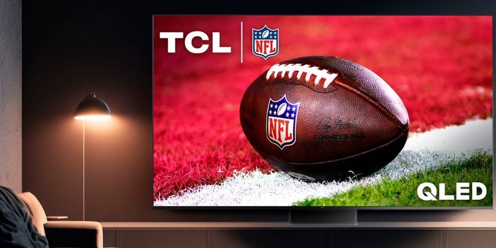 A TCL QM8 4K TV in a dark room on a TV console.