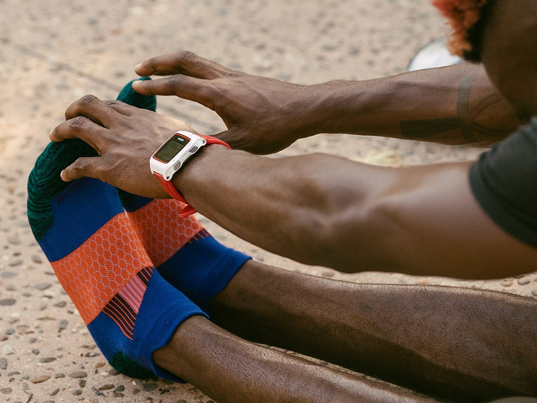 A person sitting and touching their toes while wearing color-blocked Bombas socks.
