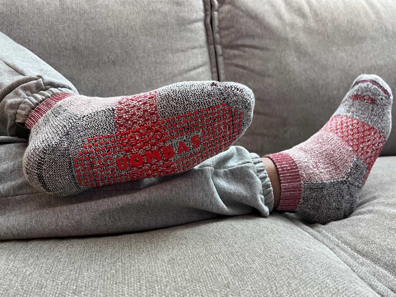 A person showing off the bottoms of their Bombas Gripper Socks while laying on a couch.