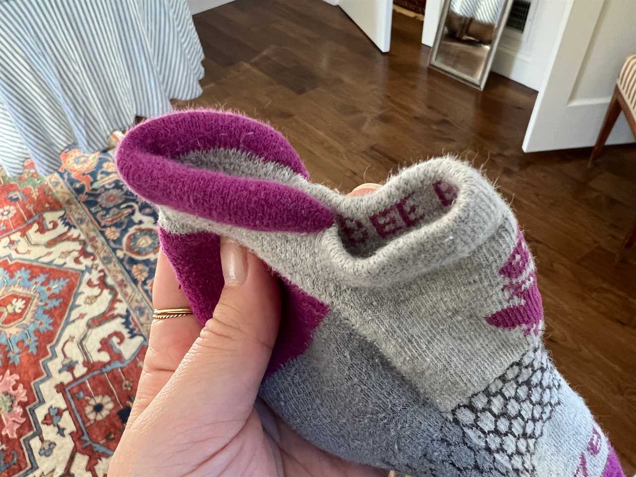 An author's hand holding the heel tab on a pair of Bombas socks.
