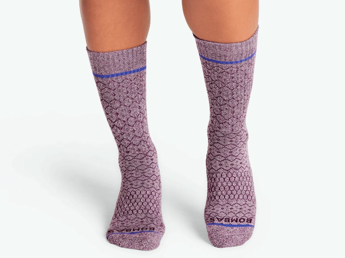 Person's feet shown wearing a pair of purple Women's Holiday Calf Socks.