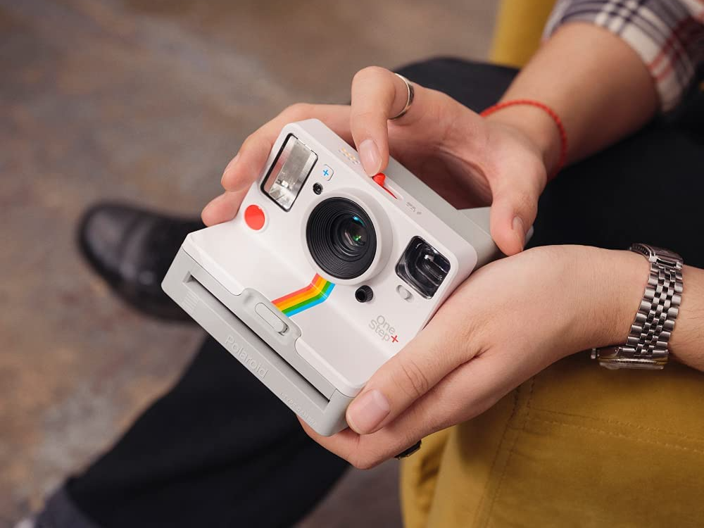 Close up of a person's hands holding the Polaroid OneStep+ White (9015) Bluetooth Connected Instant Film Camera.
