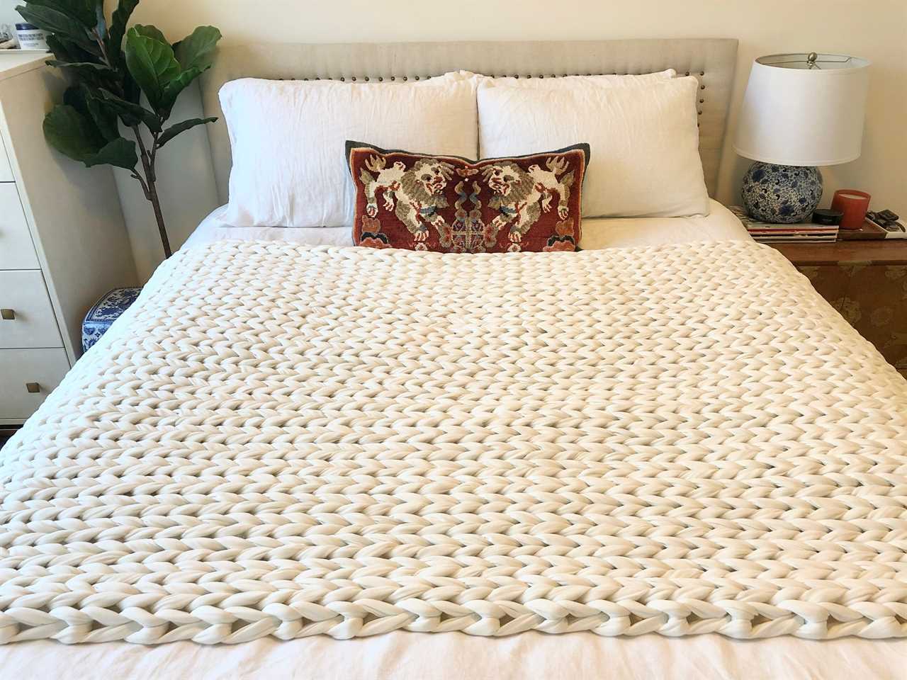 The bearaby cotton napper on a made bed, the best weighted throw blanket in 2023.