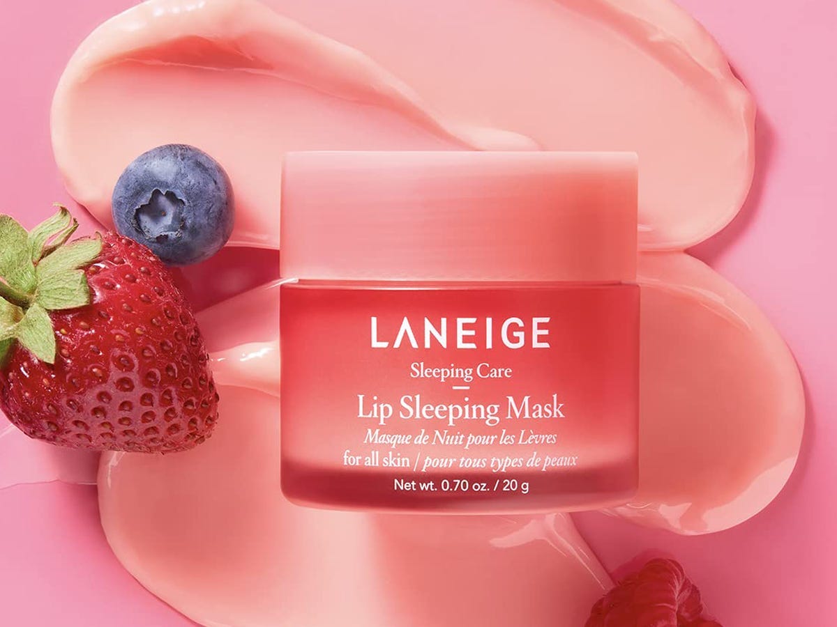 Laneige lip sleeping mask on a pink background with a strawberry and blueberry