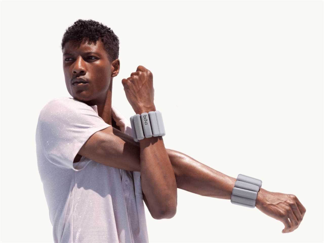 Person stretching their arm while wearing weighted Bala bangles around their wrists.