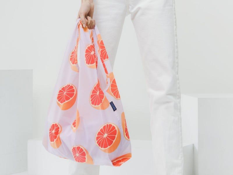 Person holding a Baggu nylong resusable bag with a grapefruit print.