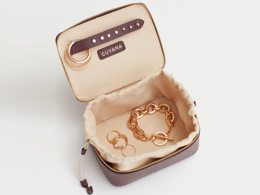 Cuyana leather jewelry case with bracelets and rings inside.