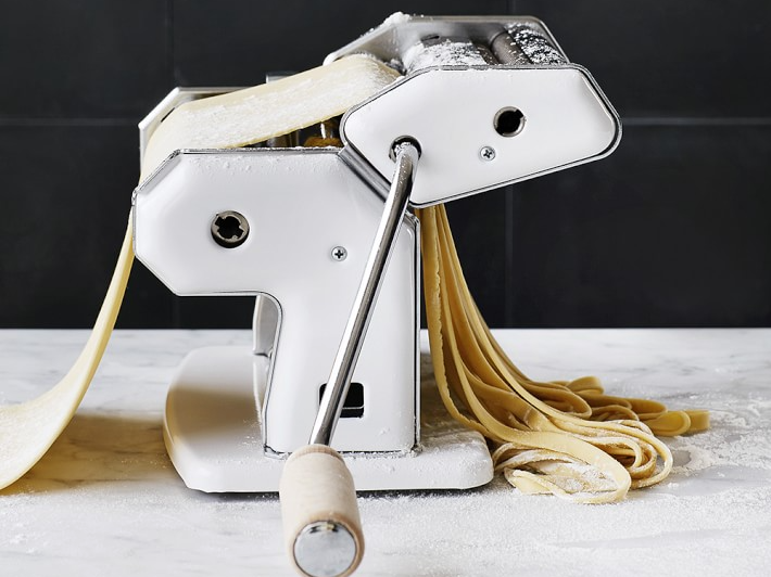 Dough being cut into noodles as it runs through a pasta machine