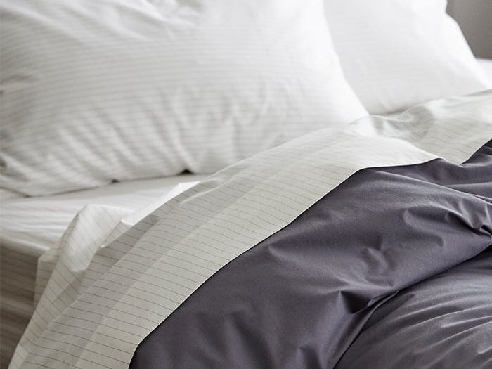 Striped Brooklinen sheets on a made bed.