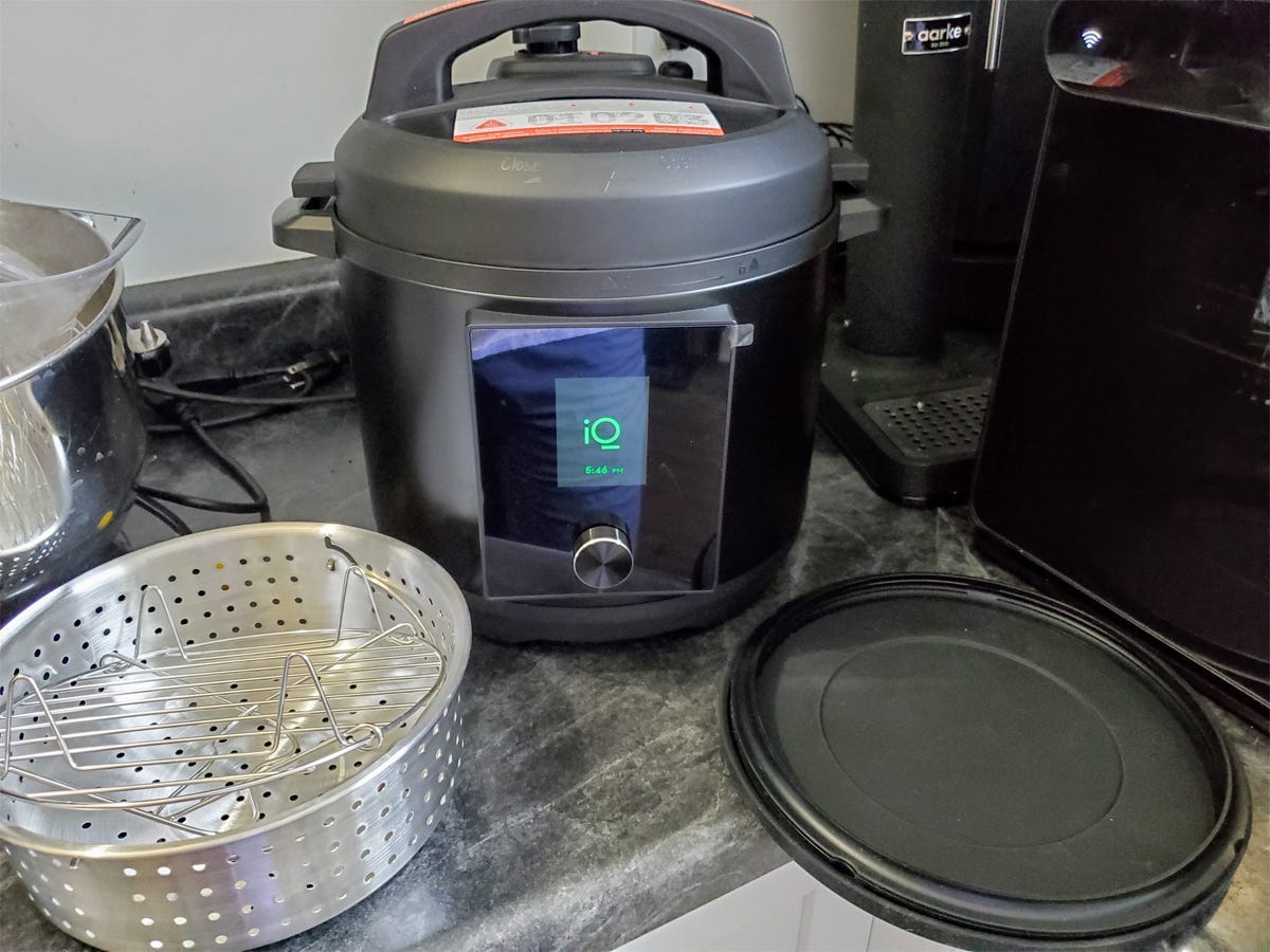 The Chef iQ Smart Cooker is displayed on a kitchen counter with its accessories.