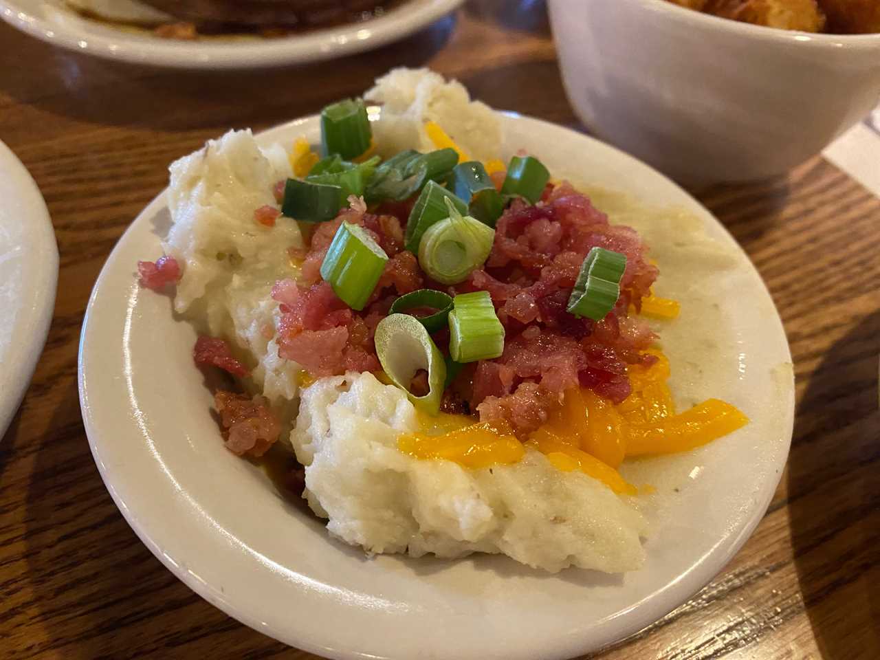 bowl of mashed potatoes with cheese, bacon bits, and green onion at cracker barrel