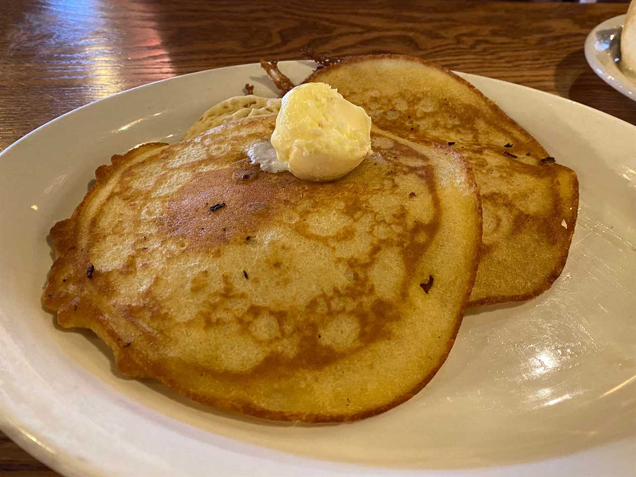 two pancakes on a plate with a ball of butter on top at cracker barrel