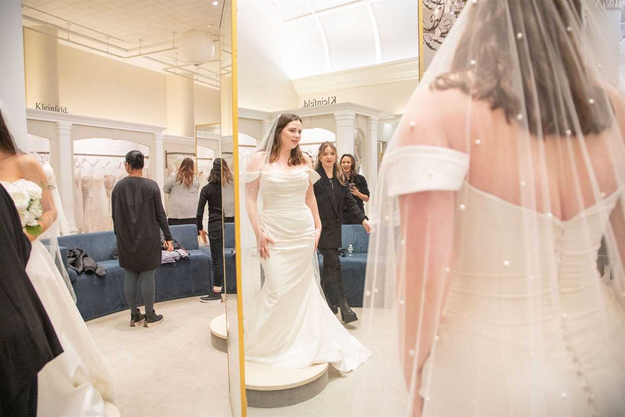 A woman in a wedding dress looks at herself in a mirror.