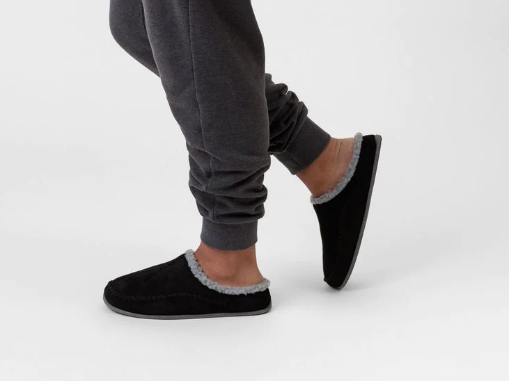 A pair of slippers worn on a person's feet as they take a step.