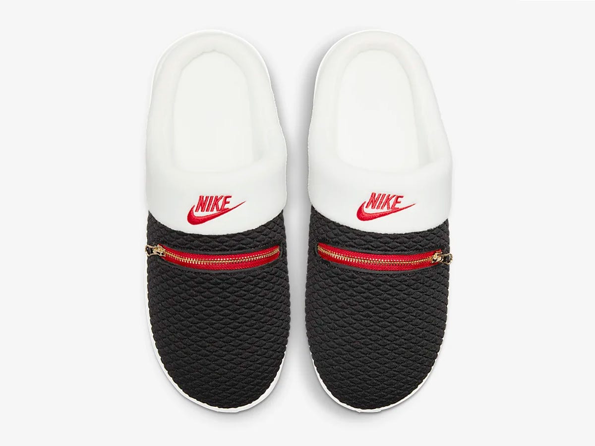 A pair of Nike Burrow Slippers that are white and black with red writing.
