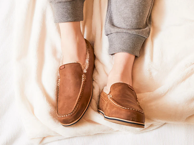 A pair of Hari Mari Hacienda LX slippers worn by a person in bed.