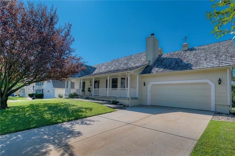 A pale yellow one-story home with front porch and one car garage.