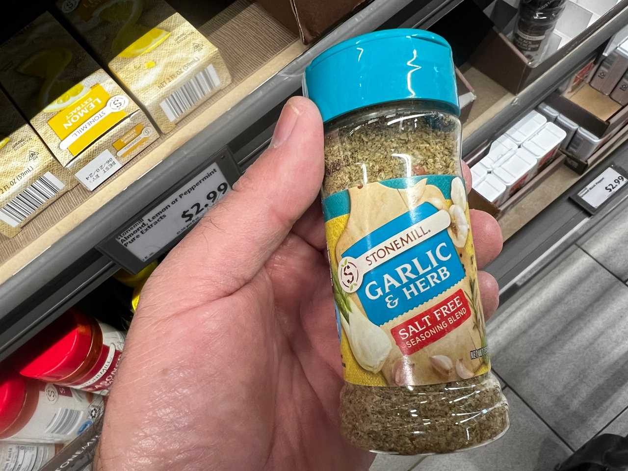 A hand holding a bottle of Stonemill garlic-and-herb salt-free seasoning. 