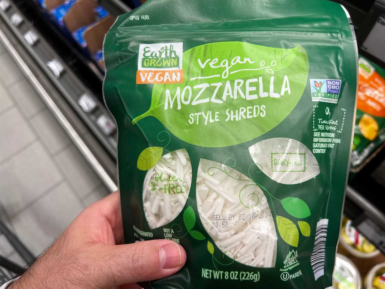 A hand holding a bag of vegan mozzarella-style shreds. 