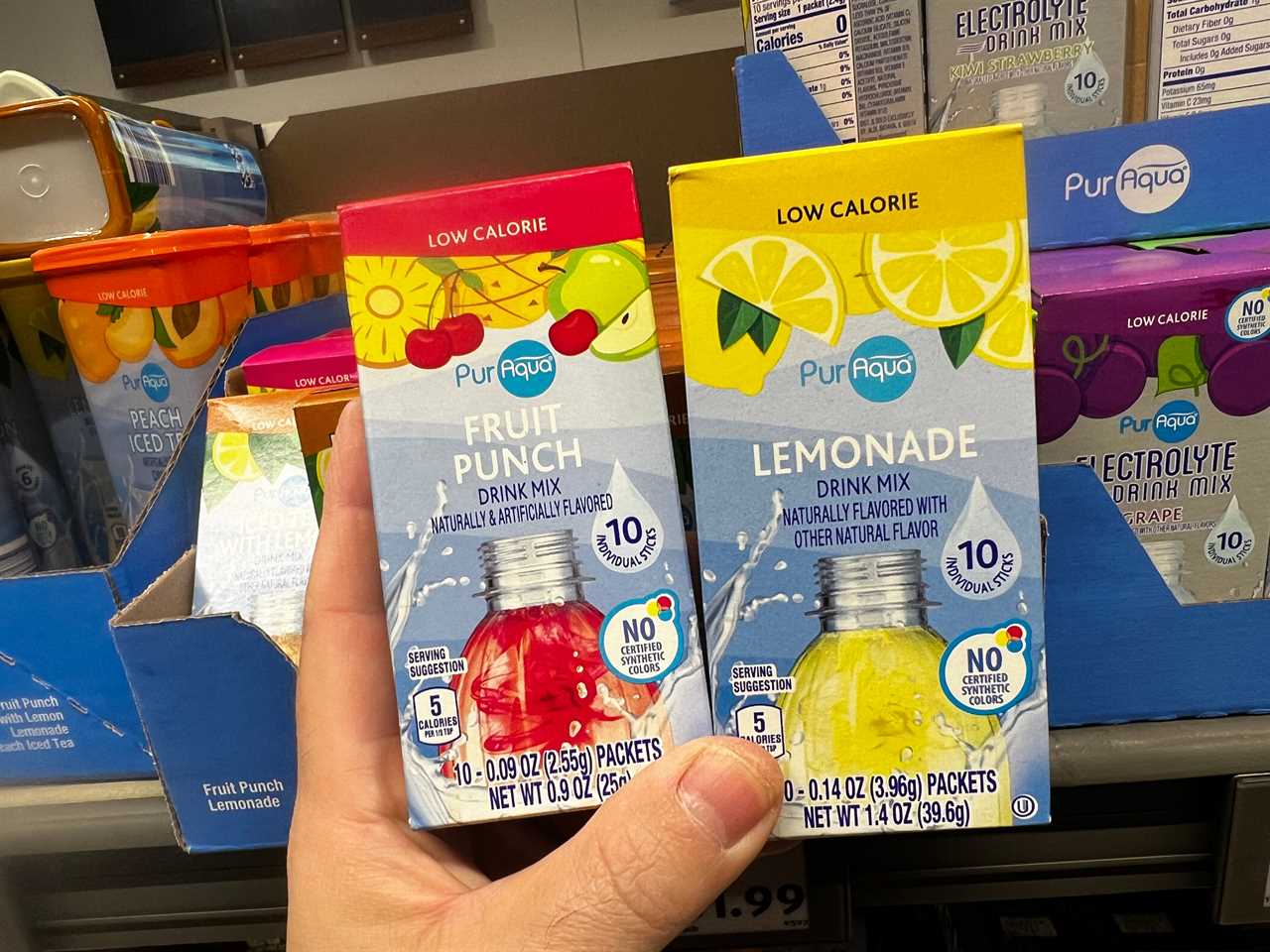 A hand holding boxes of PurAqua low-calorie fruit punch and lemonade drink mixes.