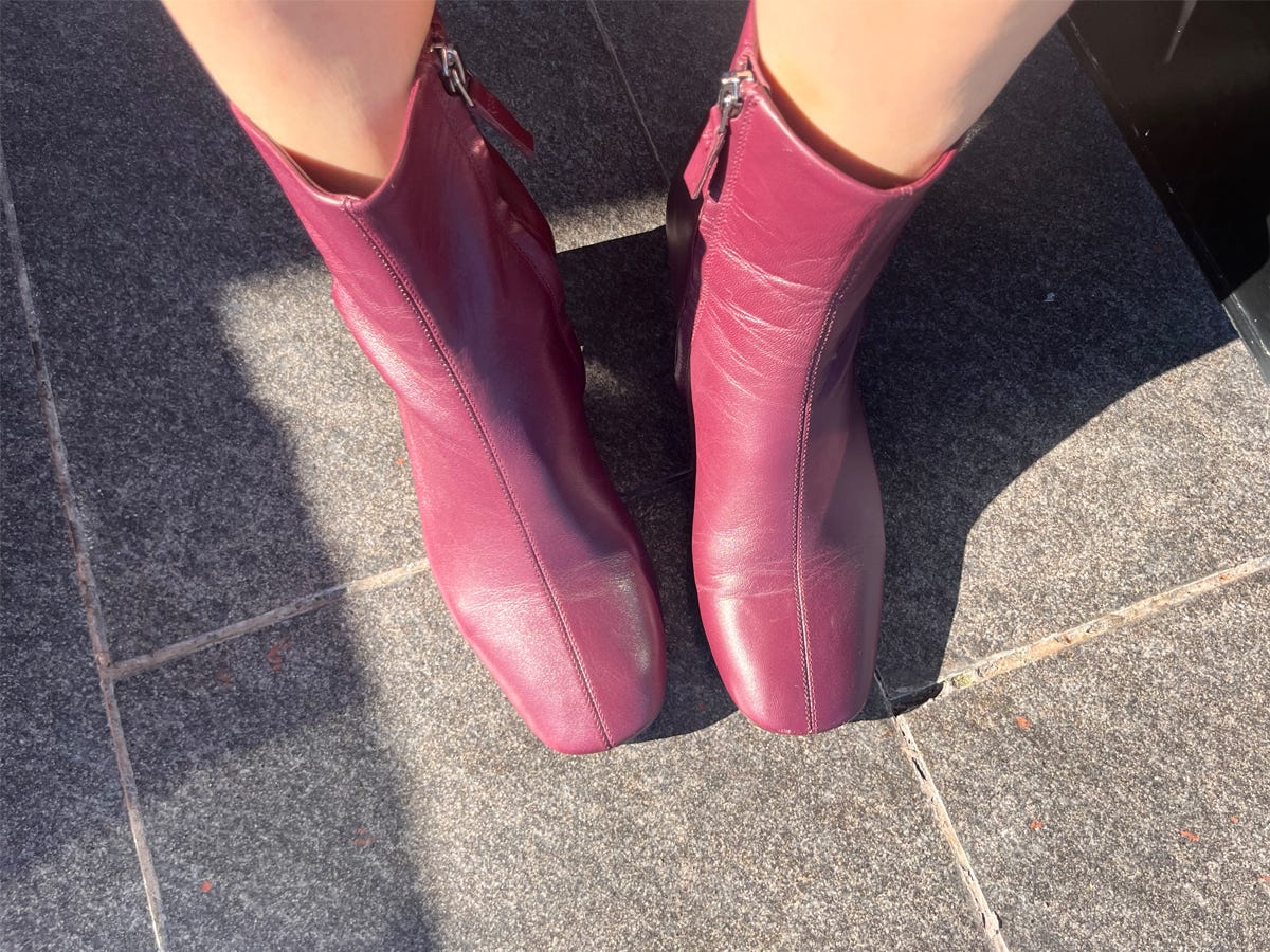 Person's feet wearing the Everlane Day Boot in maroon.