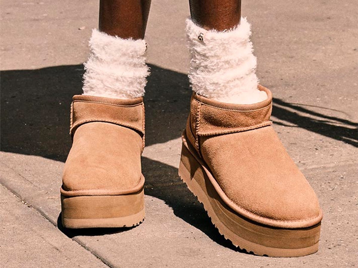 Person wearing a pair of UGG Classic Ultra Mini Platform Boots with fuzzy socks.