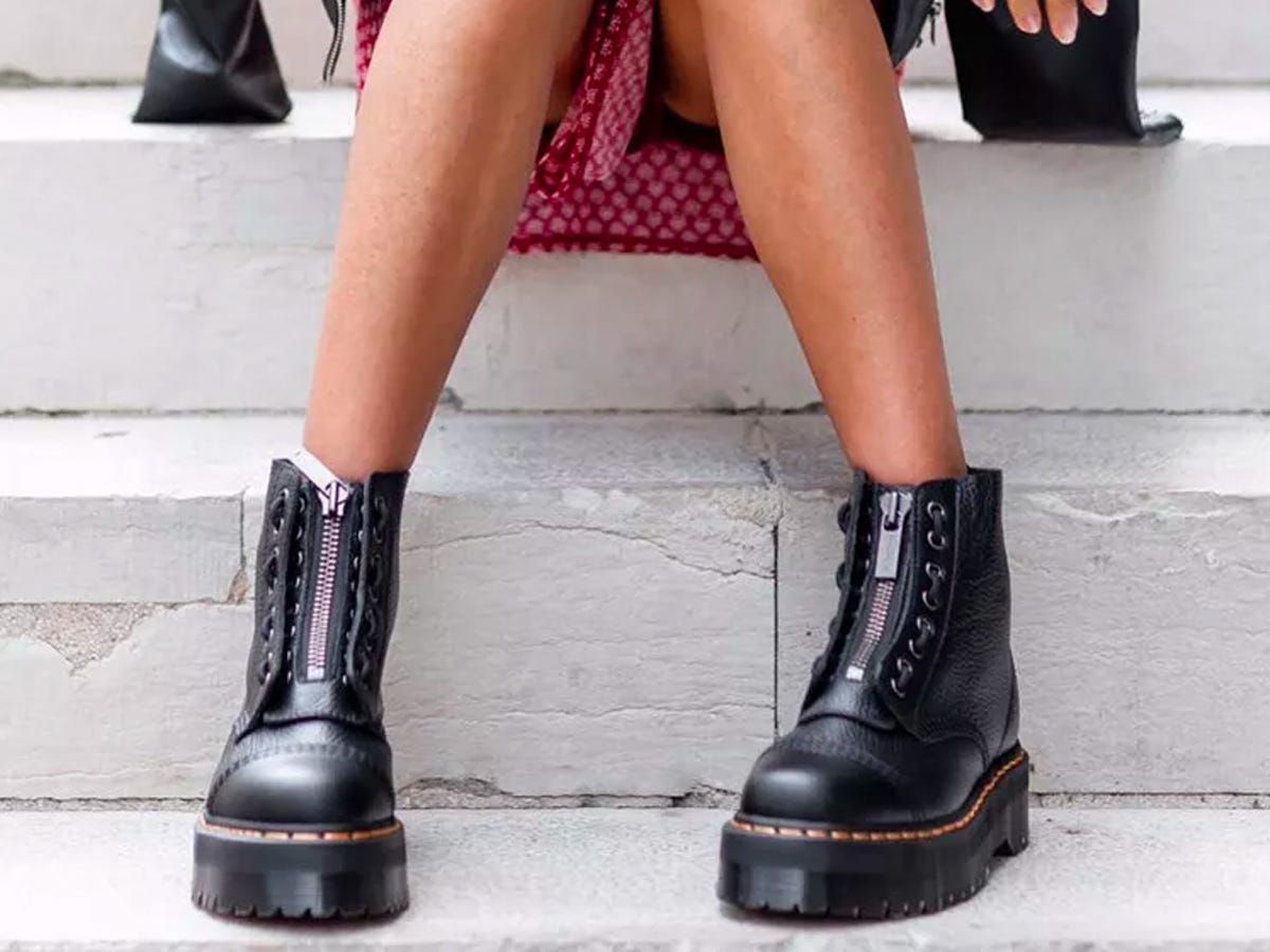 Person sitting on an outdoor staircase wearing Dr. Martens Sinclair Platform Booties with a dress.