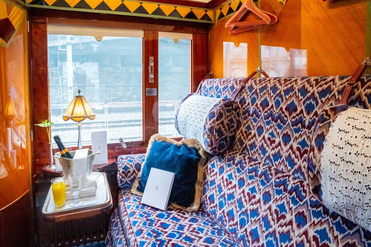 a train cabin with wood finishings and a plush red and blue couch.