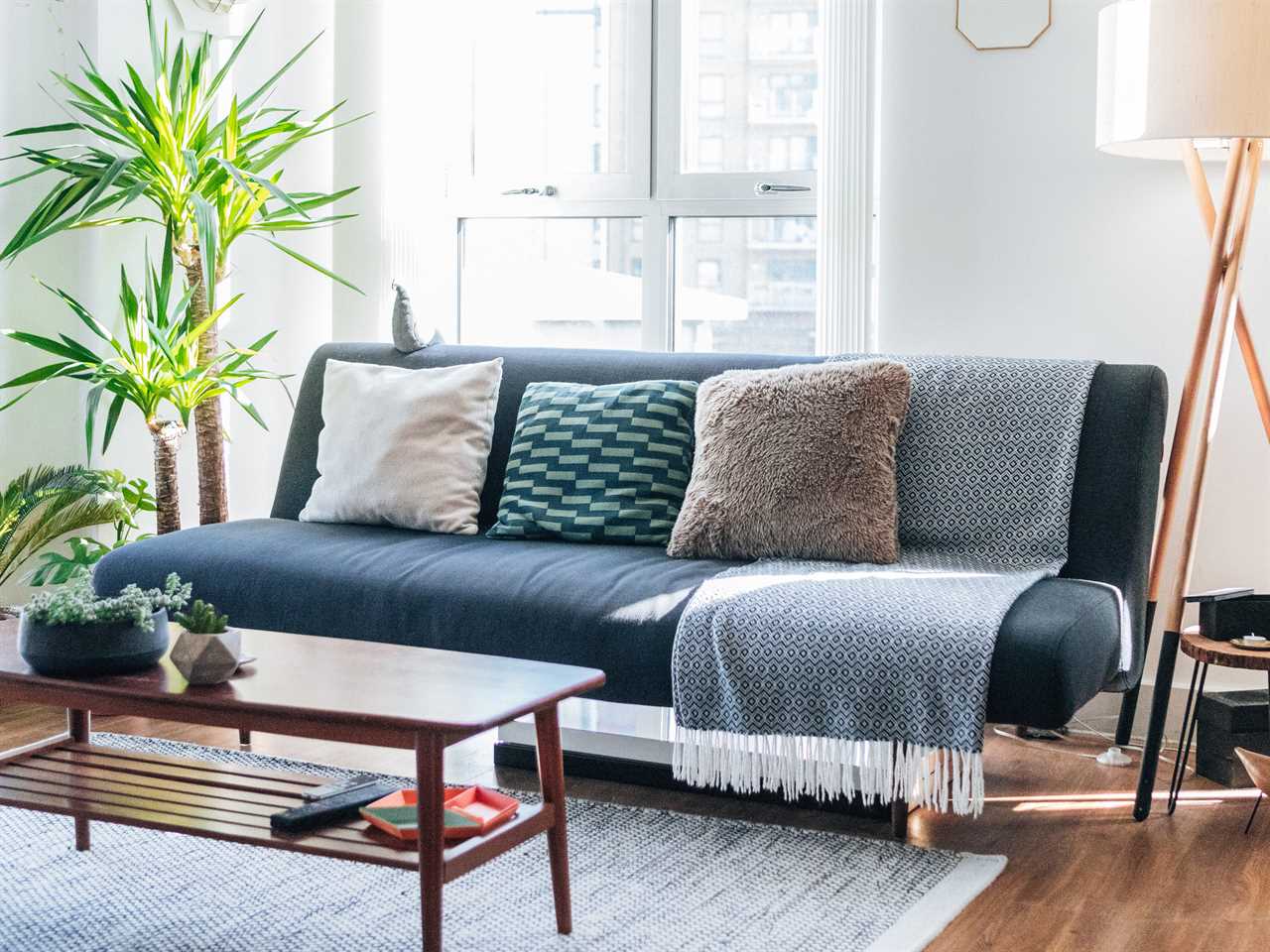 Blue couch with pillows of different materials and a throw blanket