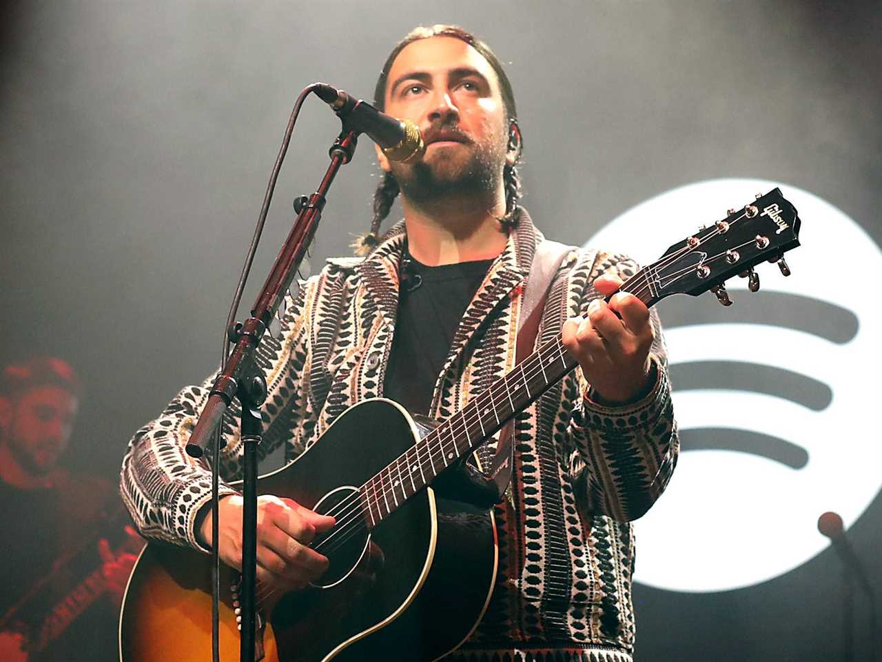 noah kahan performing on stage with a spotify logo behind him