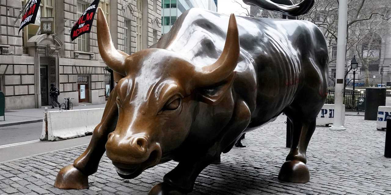 large bronze statue of bull in running stance in a brick plaza